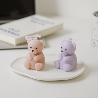 誕生日は装飾のかぎつけられるハンドメイドのテディー・ベアの形づけられた蝋燭を手作りする